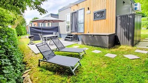 Un patio moderno al aire libre con sillones de descanso y una parrilla.