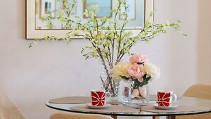 A dining area with a round glass table, four beige chairs, and a vase with flowers. - ~Weekly 15% OFF~ Modern Charm w/ Luxury Beds, Fireplace, Workspace (Luray)