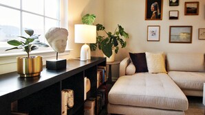 A living room with a sofa, a lamp, a plant, and a bookshelf. - ~Weekly 15% OFF~ Modern Charm w/ Luxury Beds, Fireplace, Workspace (Luray)
