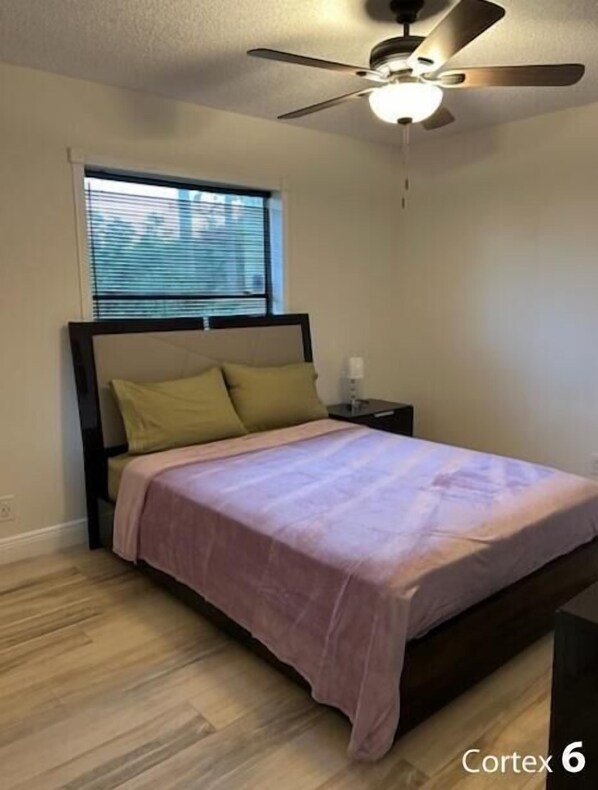 A bedroom with a bed, a nightstand, a ceiling fan, and a window with blinds. - Comfy House with Pool Near Polo Club in Wellington (Wellington)