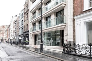 A street view with modern buildings, including a building with a glass facade and balconies. - Gorgeous Fitzrovia 1BR w/ Terrace, nr Supermarket, by Blueground (London)