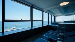En modern inredning med stora fönster som ger utsikt över en brygga och havet.