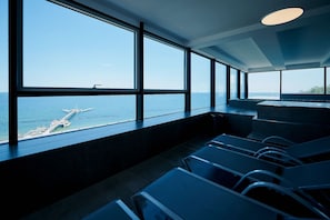 Un interno moderno con ampie finestre che si affacciano su un molo e il mare.