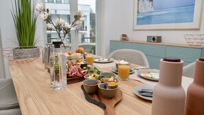 Ett frukostbord med olika sorters mat, en vas med blommor och en tavla på väggen.