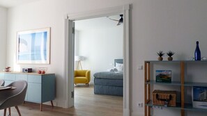 Un soggiorno moderno con angolo pranzo, una poltrona gialla, un divano blu e una libreria con oggetti decorativi.