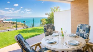 A dining area with a table set for four, overlooking a scenic view of the sea and hills. - Issea Amazing by Interhome (Torrox Costa)