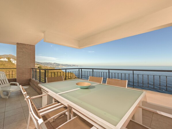 Enjoy the stunning sea views from this balcony with a table and chairs.