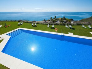 Relax by the pool surrounded by lush greenery and a stunning ocean view.