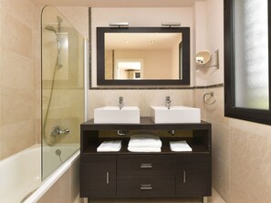 Bathroom features a glass-enclosed shower, double sinks, and a large window.