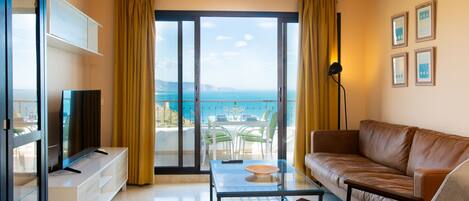 Un salon spacieux doté d’une grande porte-fenêtre coulissante donnant sur un balcon avec vue sur la mer.