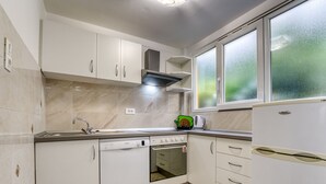 Una cocina moderna con armarios blancos, un lavavajillas Bosch, horno empotrado y refrigerador.