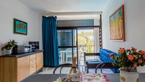 Cozinha moderna com área de jantar, varanda com vista e sala de estar com sofá.