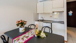 Cozinha compacta com armários brancos, pia embutida e ar condicionado.