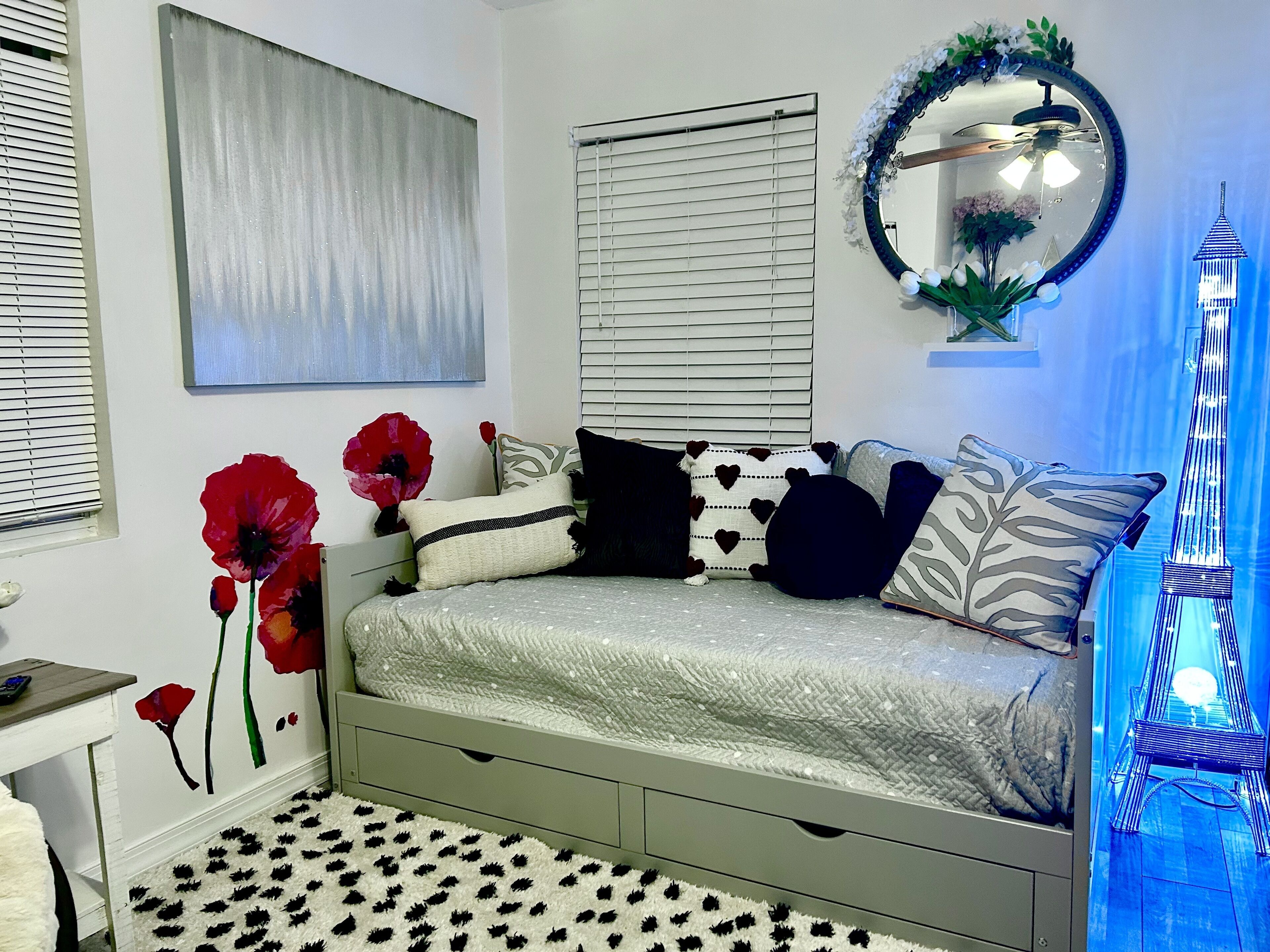A bedroom with a bed, a dresser, a mirror, and a decorative Eiffel Tower light.