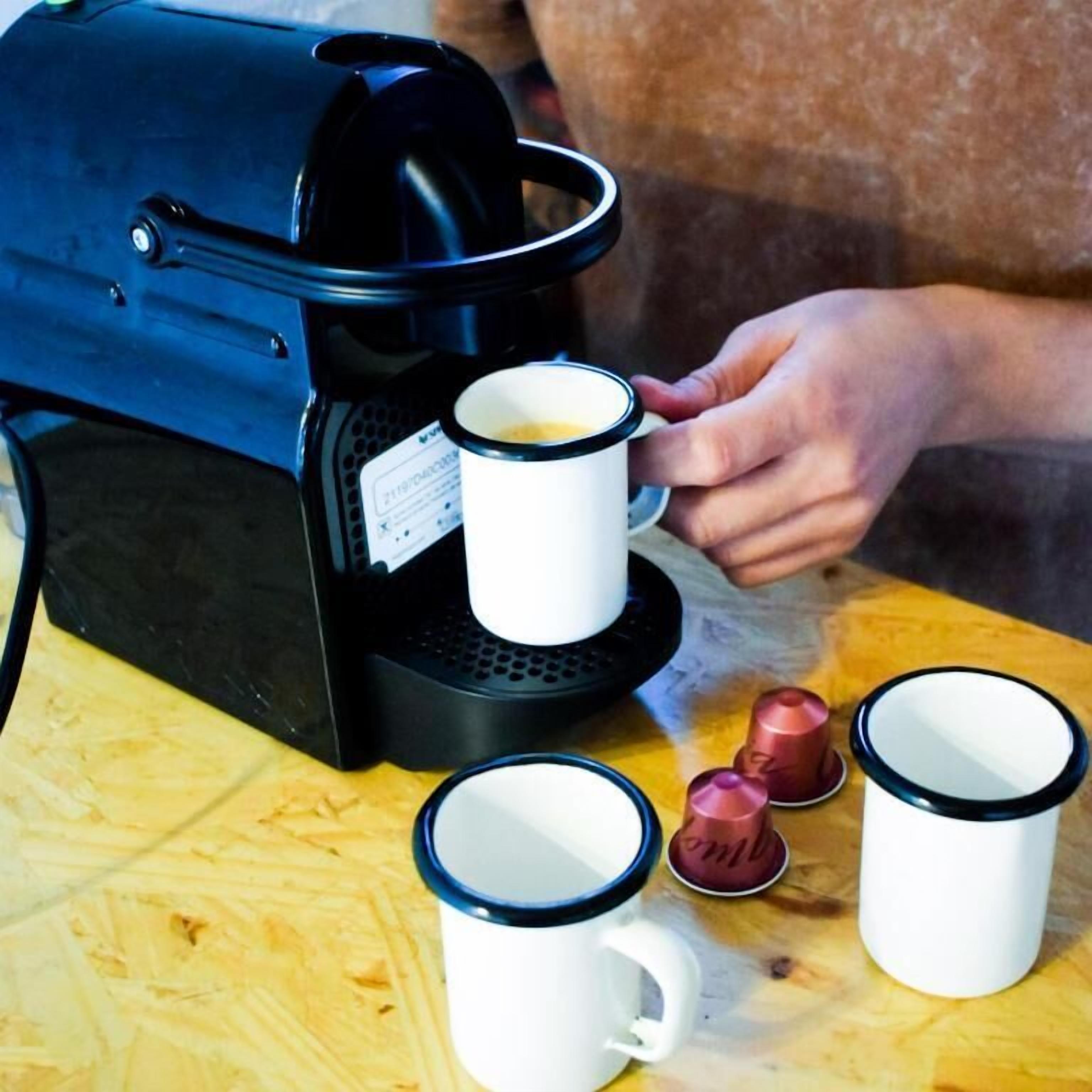Eine Kaffeemaschine mit einer Kaffeetasse auf der Tropfschale und mehreren leeren Tassen auf dem Tisch.