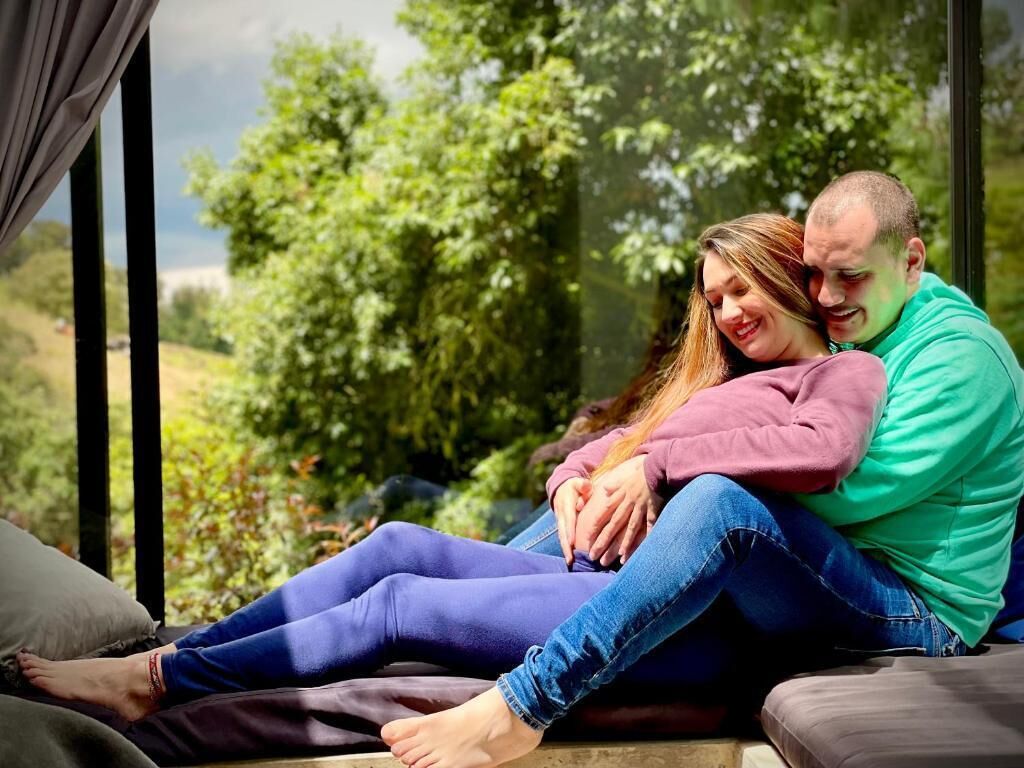 A couple sitting on a bench with a view of greenery and trees.