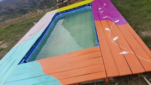 A small, outdoor swimming pool with a wooden deck surrounding it.