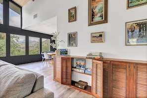 Enjoy a mountain view from the large window in this stylish living space, featuring a console table with a board game and framed artwork.