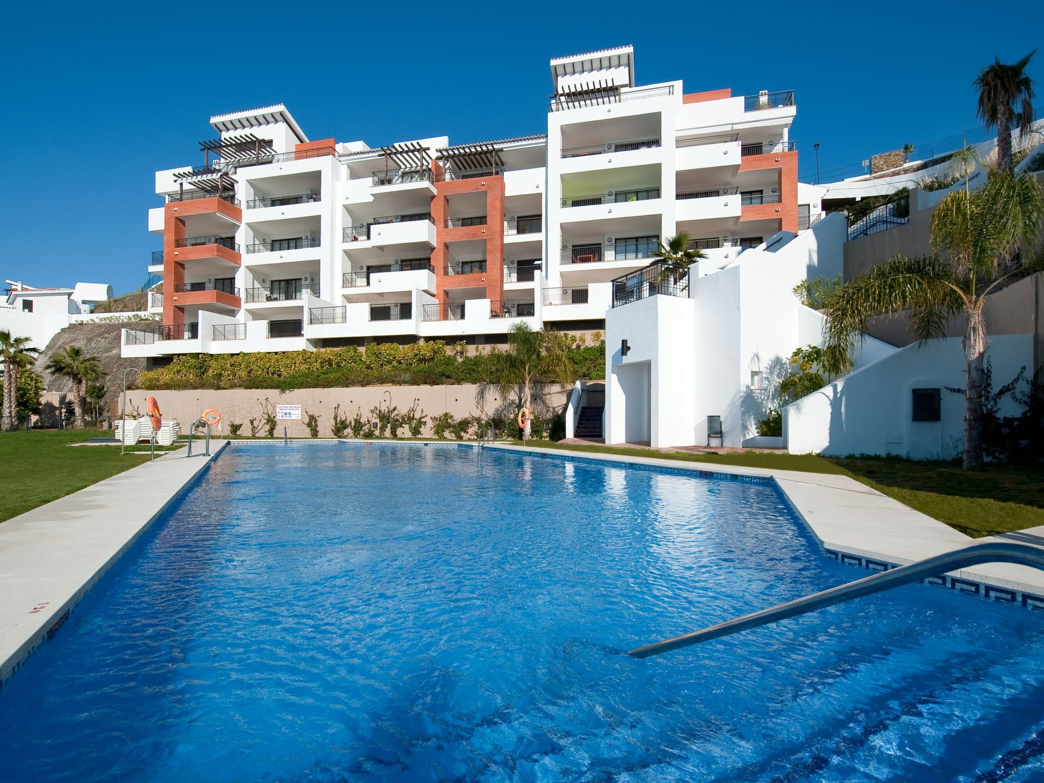 En swimmingpool med en moderne bygning i baggrunden.