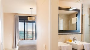 A bedroom with a balcony, a bathroom with a large mirror, and a shower. - Sea Front by Interhome (Torrox Costa)