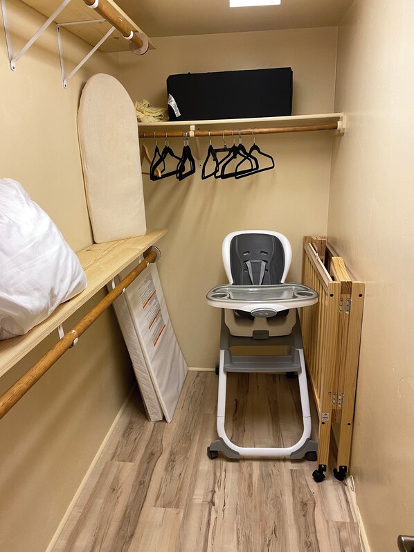 Une petite chambre comprenant un lit, un petit bureau, une chaise et une étagère avec des cintres.