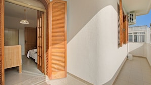 Een kamer met een houten bed, een klein tafeltje en een raam met houten luiken.