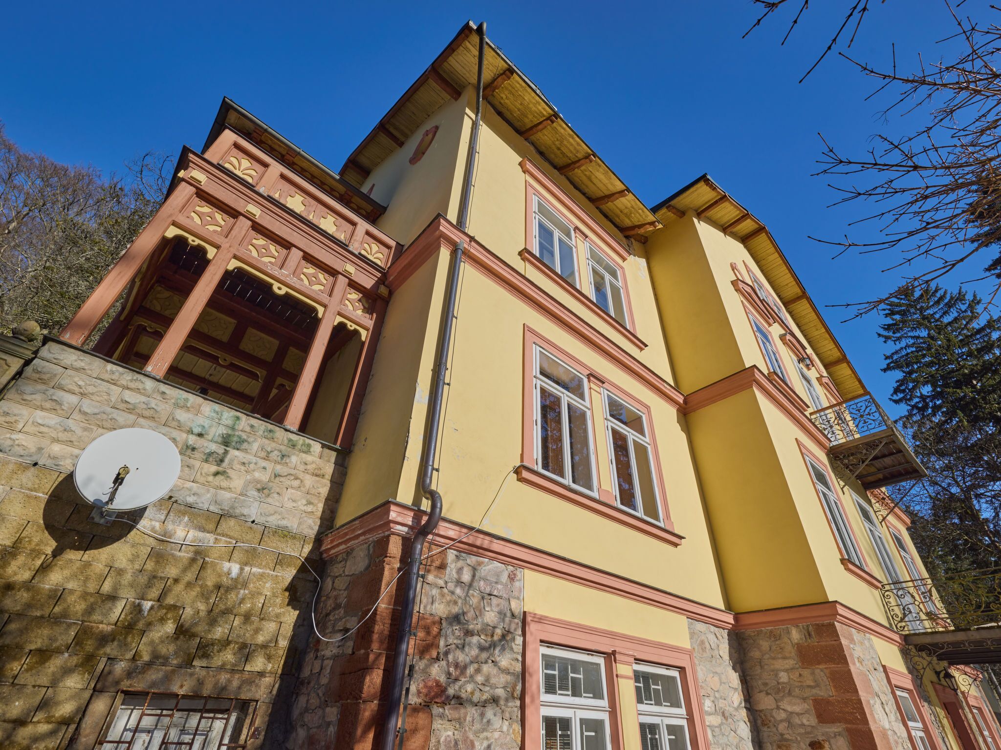 A multi-story building with a yellow facade, stone base, and decorative wooden elements.