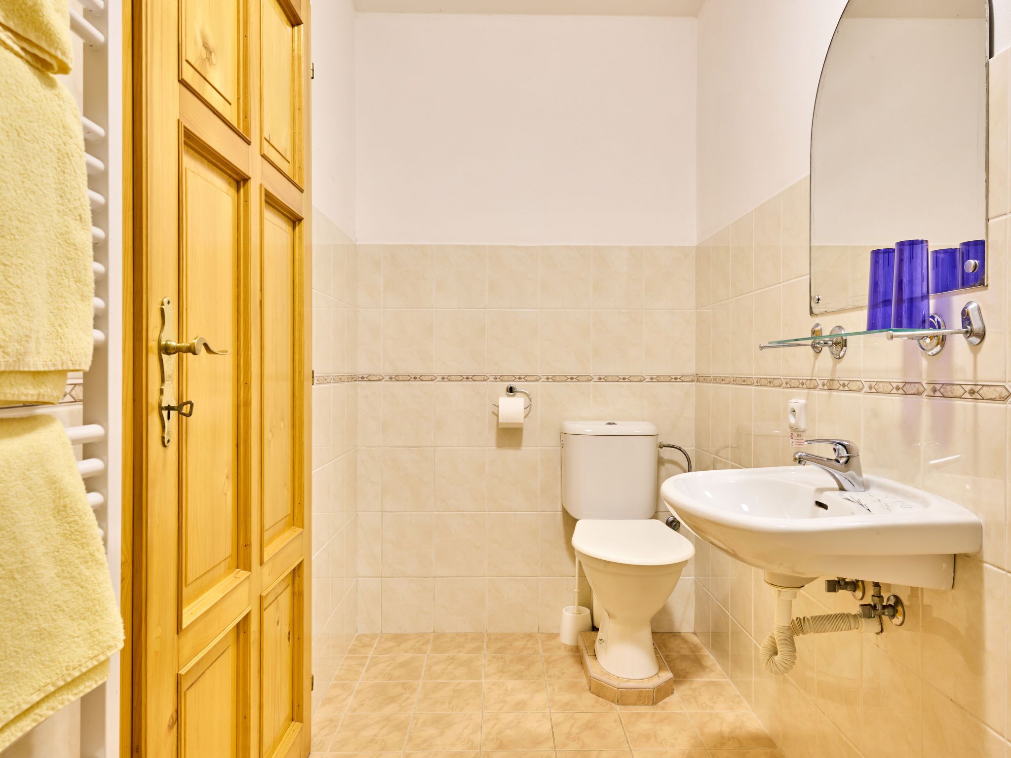 A bathroom with a toilet, sink, and wooden cabinets.