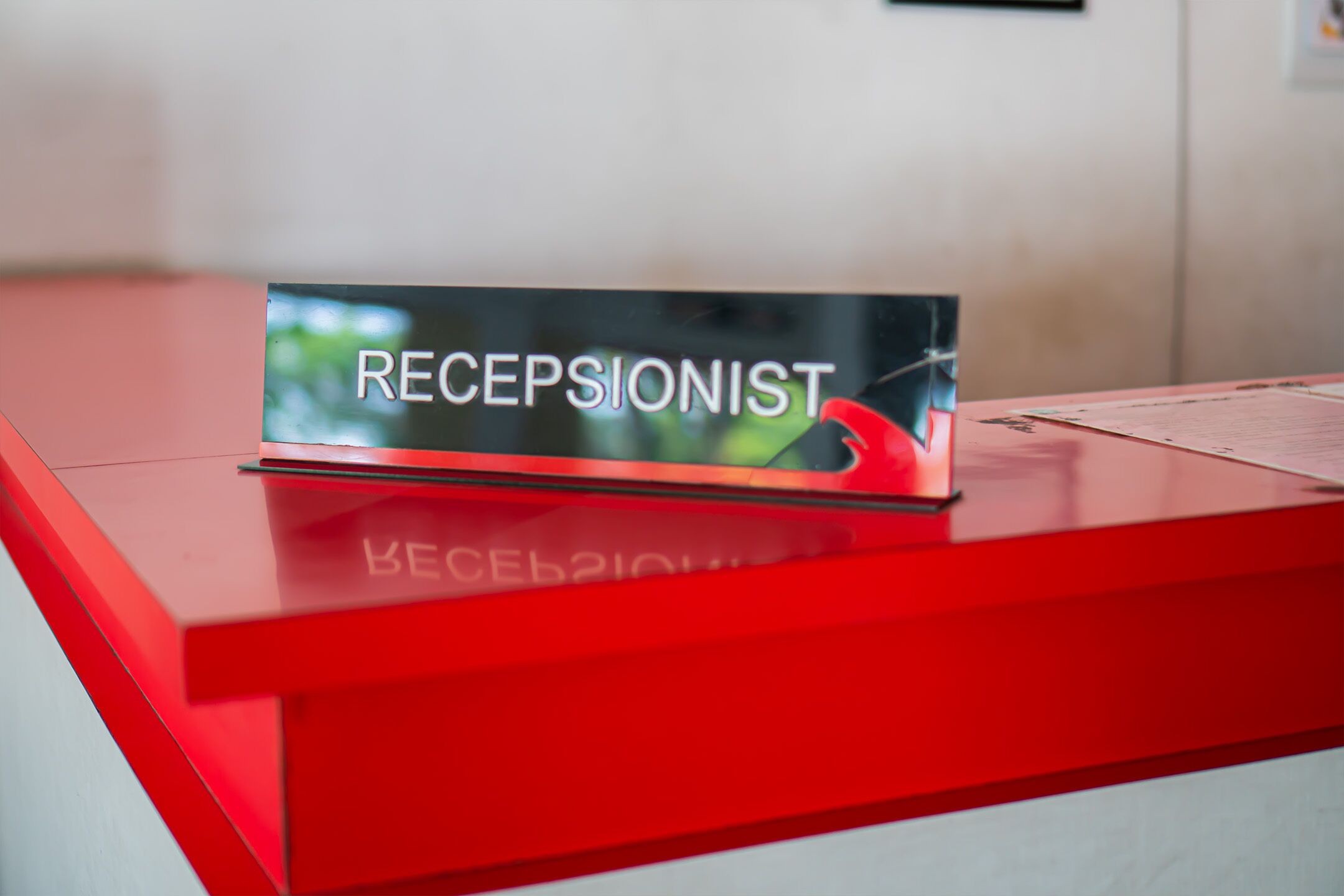 A reception desk with a sign that reads "RECEPTIONIST" and a nameplate with Cyrillic text.