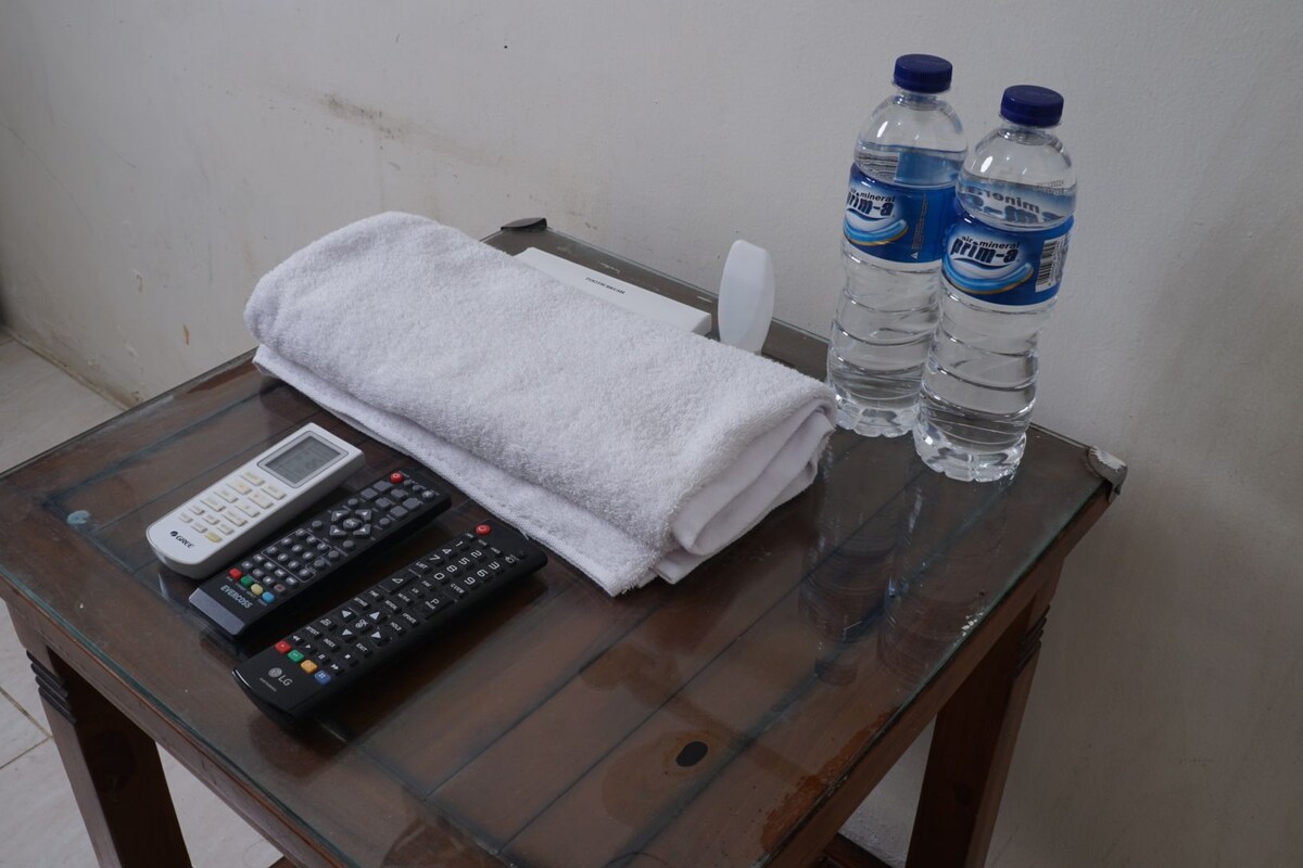 Una mesa de vidrio con una toalla blanca, dos botellas de agua y dos controles remotos.