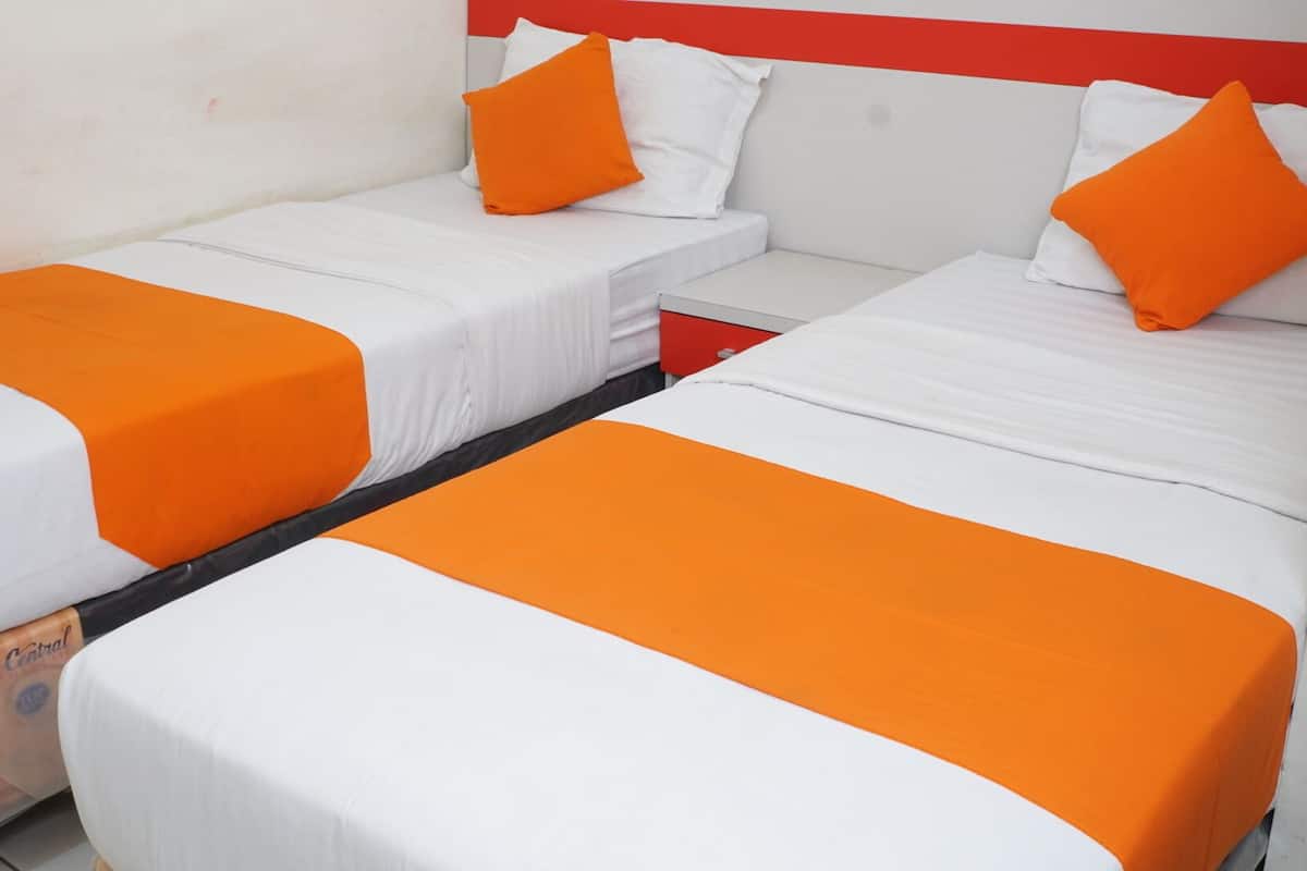 A hotel room with two beds, each with white bedding and orange accents.