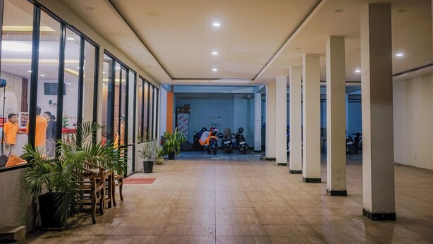 A spacious corridor with a tiled floor, large windows on the left, and a view into a room with bicycles.