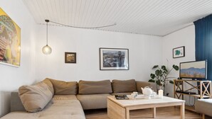 A modern living room with a sectional sofa, a wooden coffee table, and a television on a stand.