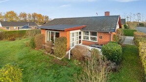 A single-story brick house with a sloped roof, a front porch, and a well-maintained lawn.