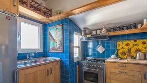 A kitchen with blue tiles, wooden cabinets, a stove, and a sink. - Santa Cecilia View by Interhome (Rome: Historical City Center)