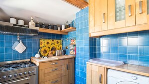 A kitchen with blue tiles, wooden cabinets, a stove, and a washing machine. - Santa Cecilia View by Interhome (Rome: Historical City Center)
