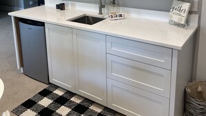 Eine moderne Küche mit weißen Schränken, einer Spüle aus Edelstahl und einem Teppich mit Schwarz-Weiß-Muster.