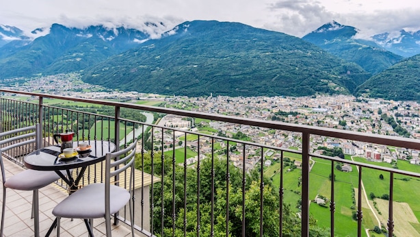 A balcony with a table and chairs overlooking a city and mountains. - Santa Croce View by Interhome (Valtellina)