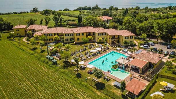 A hotel with multiple yellow buildings, a swimming pool, and a view of a lake.