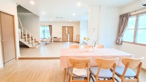 A spacious dining area with a large table and four wooden chairs, a staircase leading to another room, and a large window with curtains. - 48 House - Patong (Tambon Patong)