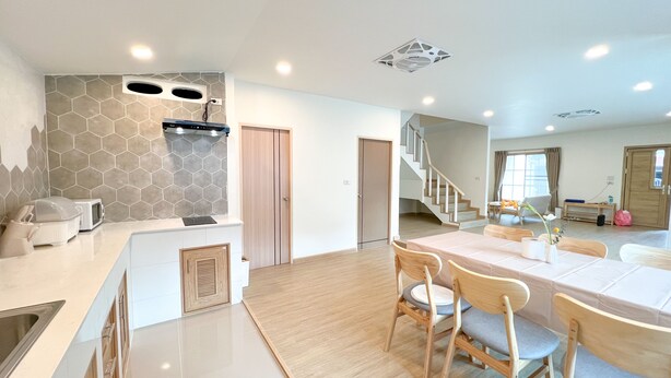 A modern kitchen with a central island, a dining area with wooden chairs, and a staircase leading to another level. - 48 House - Patong (Tambon Patong)