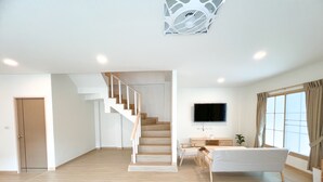 A spacious living area with a staircase, a flat-screen TV, and a large window with curtains. - 48 House - Patong (Tambon Patong)