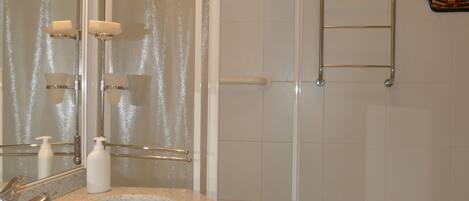 A bathroom with a granite sink, a mirror, a towel rack, and a shower area.