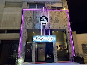 A spa with a neon sign and a marble facade.