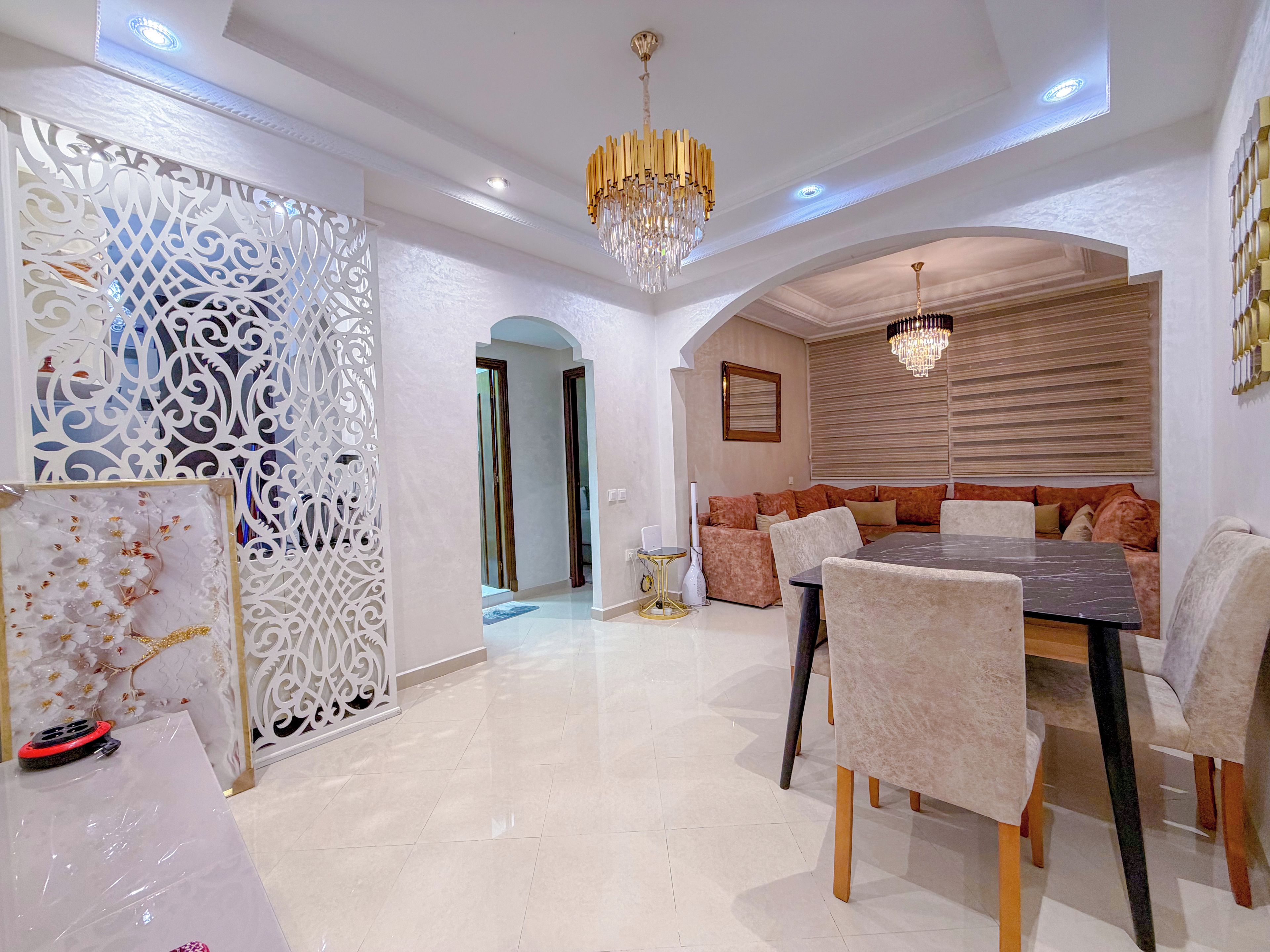 A dining area with a chandelier, a sofa set, and a decorative partition.