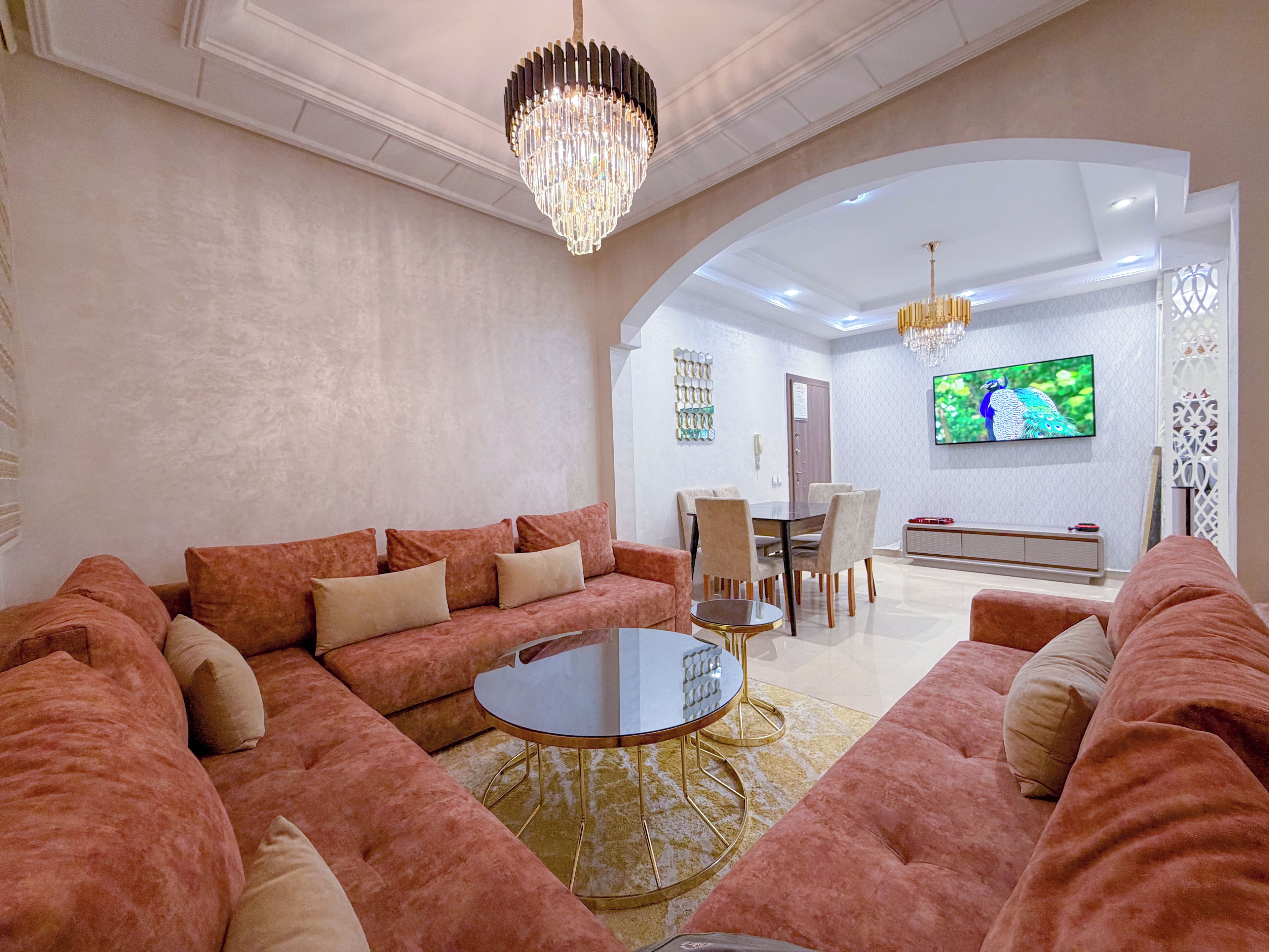 A living room with a large sofa set, a round coffee table, and a chandelier.