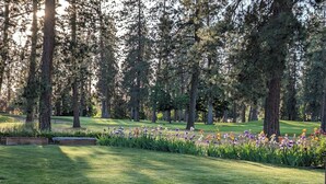 A well-maintained park with a variety of flowers, tall trees, and a grassy area. - Beautiful Golf Course Home • CDA Nest (Coeur d'Alene)