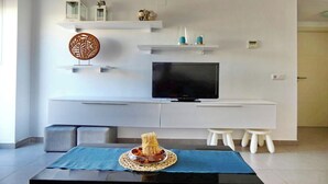 A modern living room with a flat-screen TV, white cabinetry, a blue tablecloth, and a decorative centerpiece. - El Grullo, with community pool. (Conil de la Fra.)