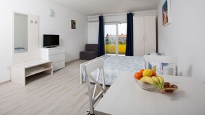 Ein modernes Hotelzimmer mit Bett, Fernseher, Schreibtisch und einer Essecke mit Obst.