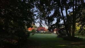 Uma casa com telhado vermelho, cercada por árvores e um gramado.